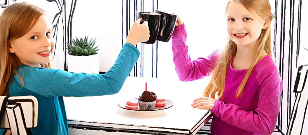 Two girls toasting with mugs over a cupcake at 94 Take the Cake